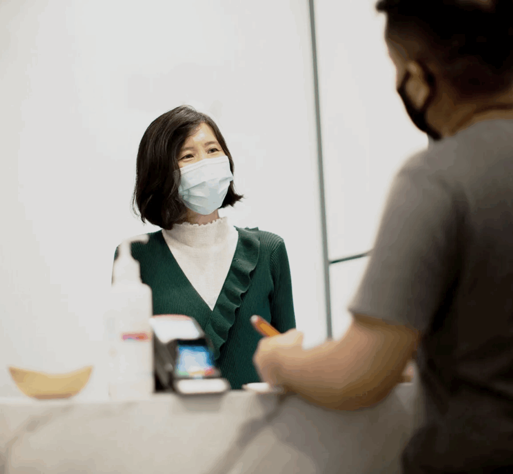 Hand Therapy Associates therapist wearing mask behind reception desk interacting with a client.